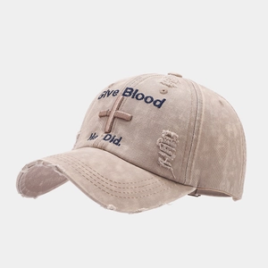 Detail of distressed khaki baseball cap with blue Give Blood embroidery and cross symbol