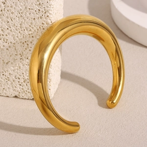 Close-up of a 18K gold-plated stainless steel open bangle resting on a natural stone