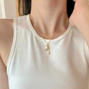 Gold necklace with cubic zirconia moon and star pendant worn by a model