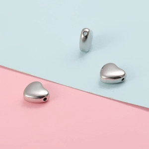Macro shot of three polished silver heart-shaped stainless steel beads with thru-holes
