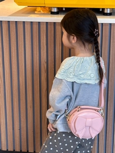 Detailed view of children's pink round crossbody bag with a large bow on the back