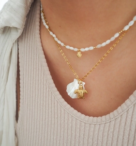 Detail of layered starfish and seashell charms on gold necklace with white beads