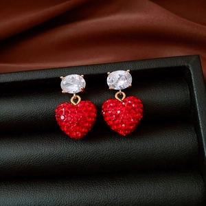 Vue détaillée de boucles d'oreilles cœur avec cristaux rouges et finition dorée sur soie