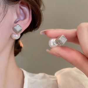 Macro shot of silver cube earrings with cubic zirconia and a large pearl backing