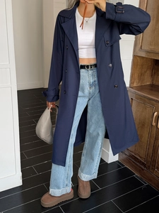 Dettaglio di un trench doppiopetto blu navy con cintura e dettagli cinturini ai polsi