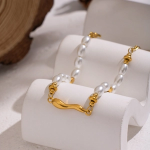 Detailed macro view of baroque pearl and 18K gold plated metal bracelet on stone display