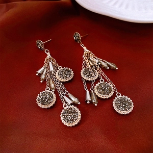 Gros plan de boucles d'oreilles ethniques à pompons avec cristaux gris et chaînes