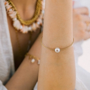 Macro shot of minimalist pearl bracelet with fine gold chain worn on female wrist