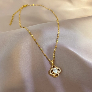 Macro shot of gold clover pendant with crystals on elegant purple satin background