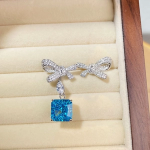 Detail of silver bow earrings with blue gemstone in a beige velvet jewelry box