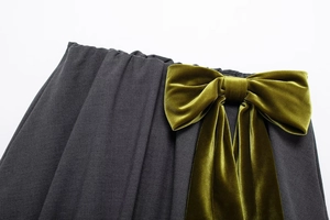 Détail d'un nœud en velours vert olive et des plis sur une mini-jupe gris foncé