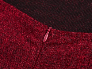 Dettaglio macro del tessuto tweed rosso scuro e della cerniera a scomparsa dell'abito