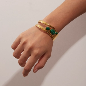 Detail of a vintage gold-finished open bangle set with three malachite texture stones