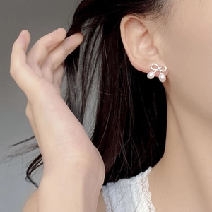 Boucles d'oreilles nœud élégantes avec perles blanches en argent 925 portées par mannequin