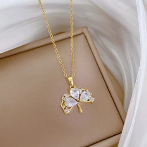 Detail of clover pendant necklace with clear crystals on beige leather and white silk