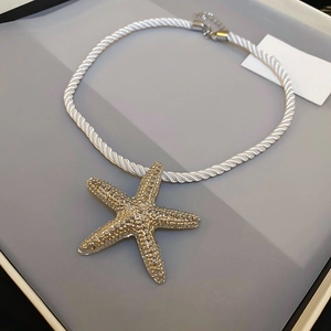 Golden starfish pendant necklace with white twisted rope chain and textured metal finish