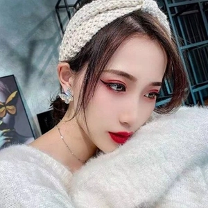 Close-up of sparkling zircon butterfly stud earrings on model with white headband
