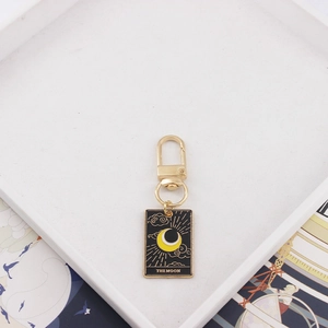 Close-up of The Moon tarot card alloy keychain with black enamel and gold details