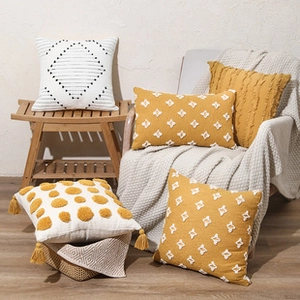 Close-up of bohemian tufted cushion covers with tassels and yellow geometric patterns