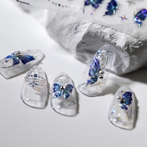 Iridescent blue butterfly nail stickers with pearls and stars on transparent nails