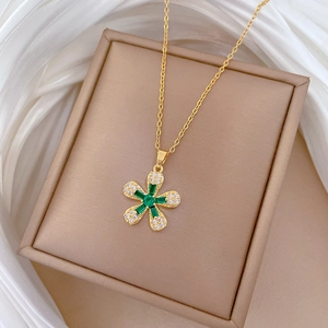Detail of gold flower pendant with green crystals and small gems on white silk