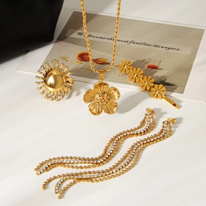 Golden jewelry set featuring flower pendant necklace, sun ring, and tassel earrings