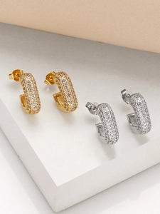 Close-up of gold and silver C-shaped earrings with pave-set sparkling zircon crystals