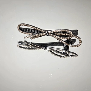 Elegant bow-shaped hair clip featuring sparkling rhinestones on a sleek black base
