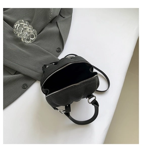 Detail of black embossed leather handbag with silver metallic zipper and sleek handle