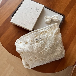 Close-up of cream lace embroidery pouch with simple wish label on a rustic wooden table