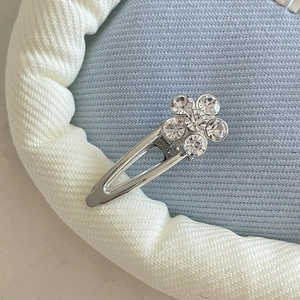 Close-up of a silver metal hair clip featuring a delicate rhinestone flower detail