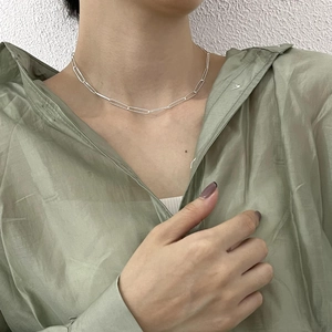 Minimalist sterling silver paperclip chain necklace styled on model with green shirt