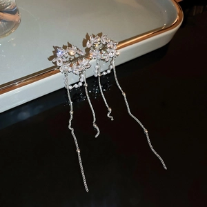 Macro detail of silver tassel earrings with sparkling leaves and delicate pearls