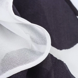 Dettaglio del tessuto in chiffon a pois bianco e nero con texture leggera plissettata
