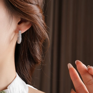 Gros plan de boucles d'oreilles créoles carrées en argent avec zircons sur le mannequin