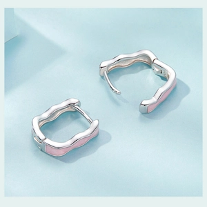 Macro shot of S925 sterling silver hoop earrings with wavy design and pink enamel detail