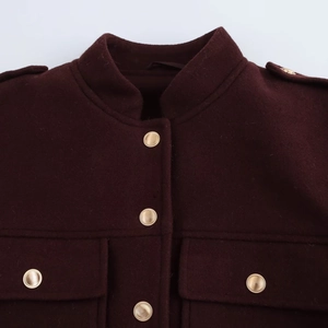 Gros plan sur la veste en laine bordeaux avec boutons dorés et poches à rabat devant