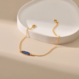 Dettaglio del braccialetto dorato con pietra preziosa ovale blu e chiusura a moschettone