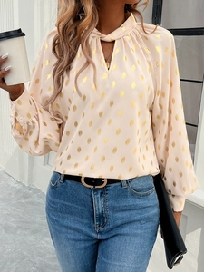 Detailed close-up of pink puff sleeve blouse with gold polka dots and V-neckline
