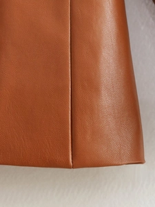 Close-up of warm brown PU leather blazer showing fine grain texture and stitching detail