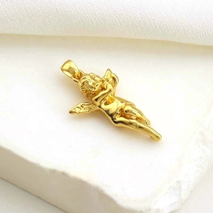 Gold angel pendant with wings on white fabric and stone background for DIY jewelry