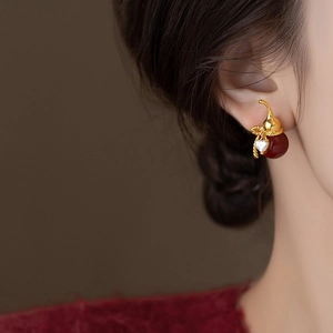 Elegant gold-plated gourd earrings with red beads and zircon on a female model