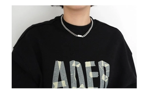 Silver cuban chain necklace with rectangular pendant worn over a black ADER sweatshirt
