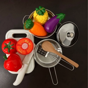 Kids kitchen role play set with stainless steel pots and toy fruits on leather background