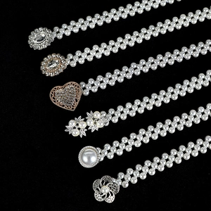 Detail view of six elegant pearl waist chains with gold and silver buckles on black