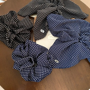 Polka dot fabric scrunchies in black and navy blue displayed on a wooden tray