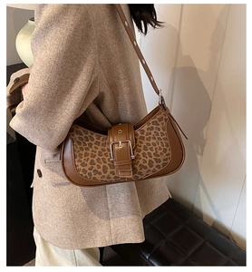 Détail du sac léopard avec finitions en cuir marron et boucle métallique sur la sangle