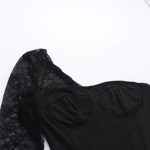 Détail du haut noir asymétrique montrant la manche en dentelle et les coutures corset