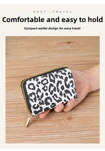 Close-up of leopard print card wallet with gold metal zipper on a wooden table