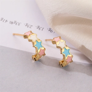 Close-up of gold-plated C-shaped earrings with colorful enamel stars in pastel tones